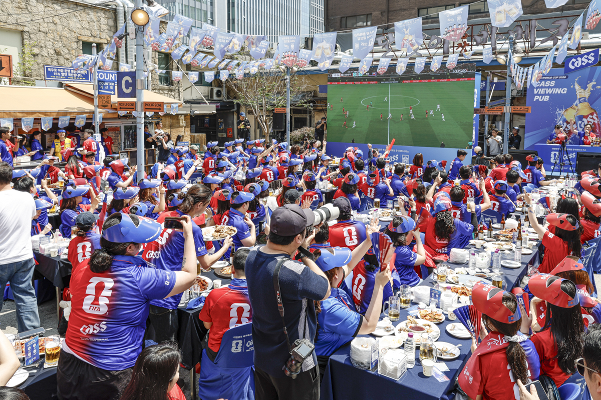 카스 뷰잉펍에서 대형 스크린으로 대한민국 축구 경기를 함께 관람하는 축구 팬들