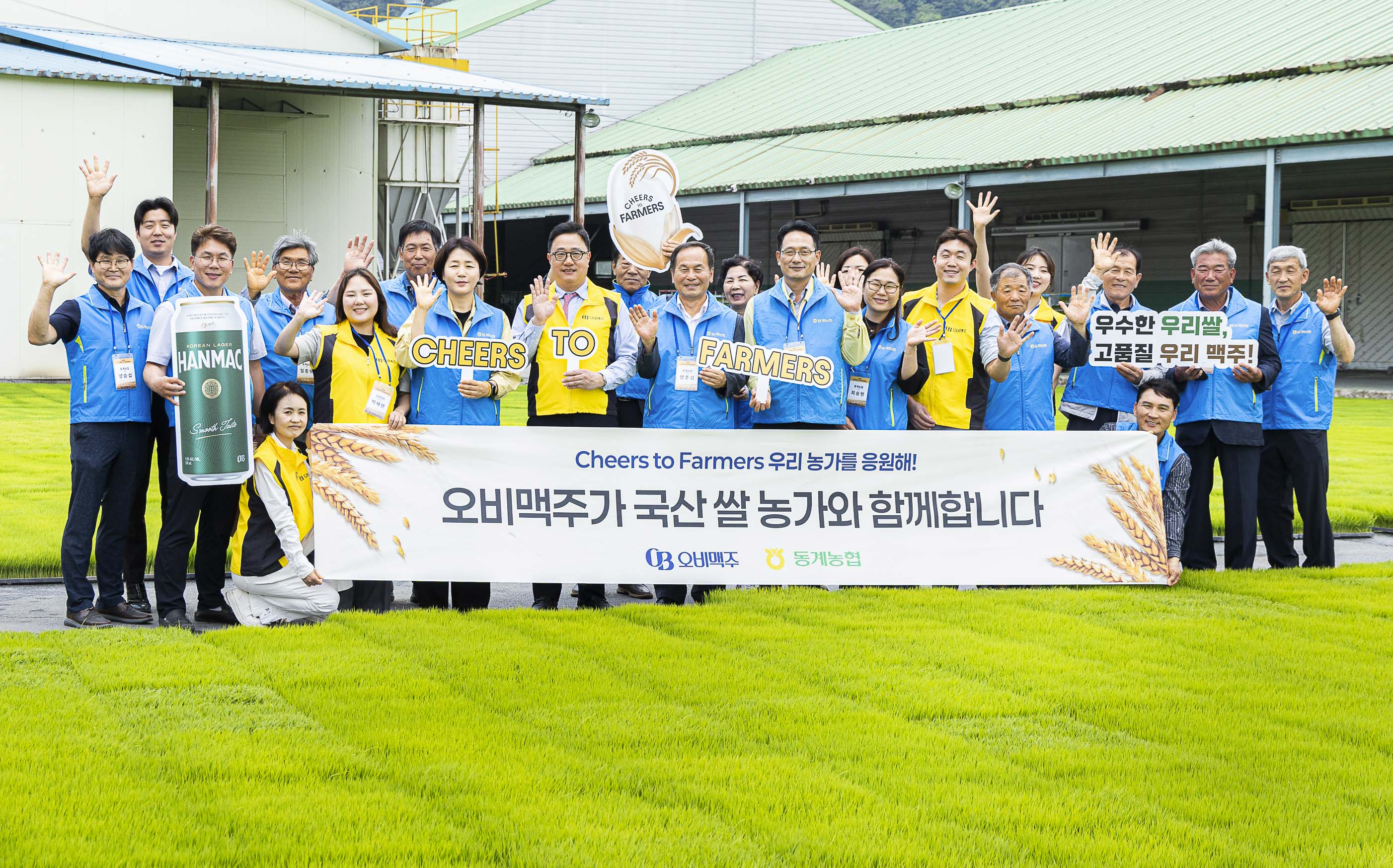 오비맥주와 동계농협이 함께하는 Cheers to Farmers 캠페인 행사에서 관계자들이 국산 쌀 농가 지원을 알리는 현수막을 들고 단체 사진을 촬영하는 모습